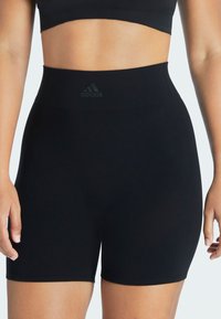 Schwarze hochgeschnittene Shorts aus dehnbarem Material mit einer glatten Textur und dem schwarzen Adidas-Logo am Bund.