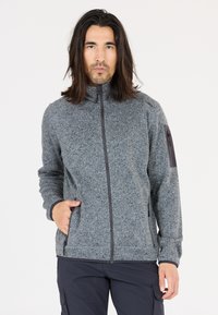Grå fleece zip-up jakke med høj krave, sidelommer og en subtil tekstur. Har mørkegrå accenter på ærmerne.