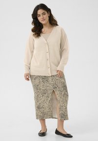 Beige cardigan with v-neck and button closure, paired with a patterned leopard print midi skirt featuring a side slit. Black flats complete the look.