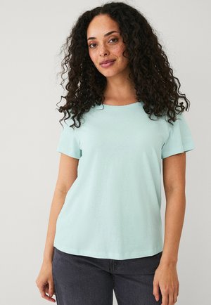 Lichtblauw T-shirt met korte mouwen, gemaakt van zachte katoen, met een ronde halslijn en een relaxte pasvorm, gecombineerd met donkergrijze jeans.