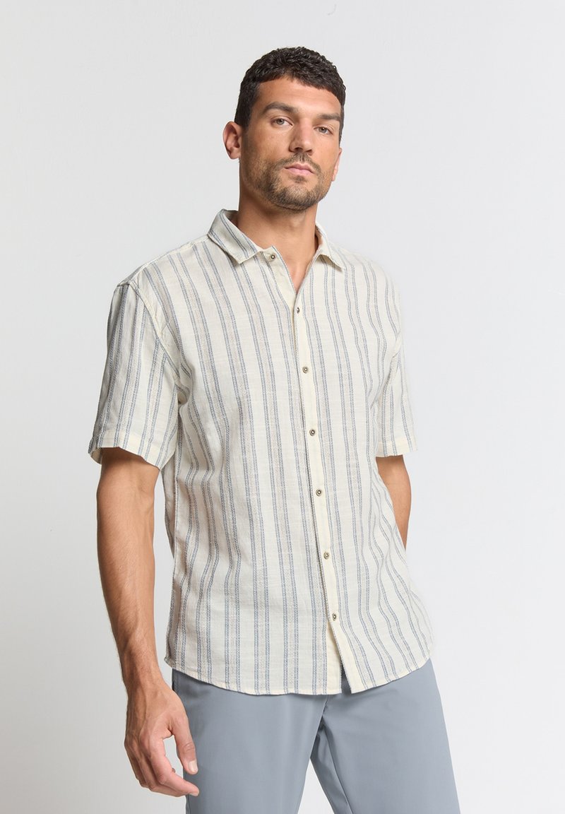 Korte mouw shirt in lichtbeige stof met blauwe verticale strepen en een knoopsluiting aan de voorkant; heeft een puntige kraag en een rechte zoom.