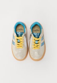 Glittery silver sneakers with blue accents, yellow laces, and zip closure. Rounded shape with a gum sole and decorative stitching.