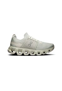 Baskets de sport gris clair avec une tige en tricot respirant, un design texturé et une semelle blanche contrastante présentant des segments découpés pour plus de flexibilité.