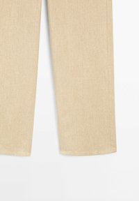 Pantalon beige à jambes droites avec coutures visibles sur fond blanc, présenté du milieu du mollet jusqu'à l'ourlet inférieur.