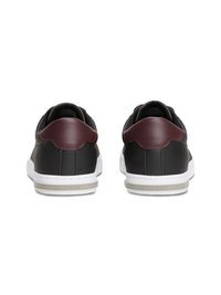 Schwarze Ledersneaker mit einem burgunderfarbenen Absatz, weißer Gummisohle und subtilen Nähten. Einfaches, niedriges Design.