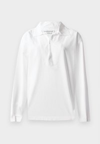 Biała, długorękawowa koszulka polo wykonana z bawełny. Posiada szeroki kołnierz oraz półzamknięcie na zamek. Gładka tekstura i luźny krój.
