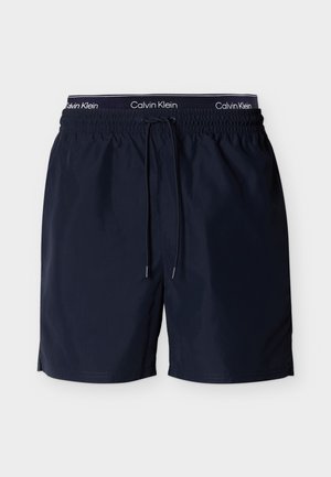 Bañador corto azul marino con cintura elástica, cordón negro y logo de Calvin Klein en el interior de la cinturilla.