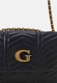 Sort quiltet læder håndtaske med guld kædestropp og guld "G" logo emblem på frontklappen.