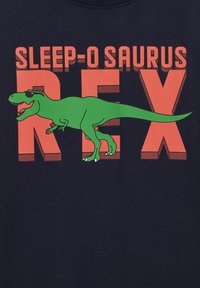 Temno modra majica s grafiko zelene Tyrannosaurus rex, ki nosi sončna očala, obkrožena z drzno oranžno napisom "SLEEP-O SAURUS REX."