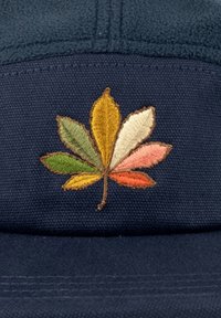 Dark blue cap with a textured fabric featuring an embroidered multi-colored leaf design in shades of green, yellow, orange, and pink.