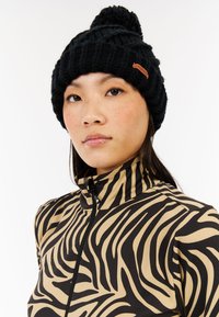 Berretto di maglia nero con un pom-pom in cima e un motivo testurizzato. Presenta una piccola etichetta con logo marrone sul lato.