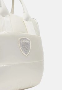Borsa a spalla bianca trapuntata con texture liscia, caratterizzata da una toppa con logo a scudo perforato e robuste maniglie corte.
