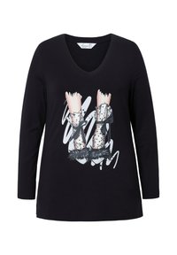 Langsleeve, zwarte V-hals T-shirt met een grafisch ontwerp van roze benen in metallic laarzen met zwarte bontafwerking en witte abstracte accenten.