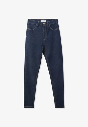 Jeans skinny in denim blu scuro con vita alta, cinque tasche e cuciture a contrasto color tan. Presentano una chiusura frontale con bottone e zip.