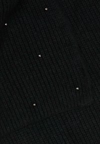 Schwarzer, gerippter Strickstoff mit kleinen metallischen Verzierungen, die über die Oberfläche verteilt sind und Textur sowie visuelles Interesse erzeugen.