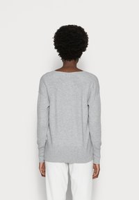Pullover grigio chiaro a maglia con scollatura ampia, maniche lunghe e vestibilità comoda. Presenta una texture a coste lungo i bordi.