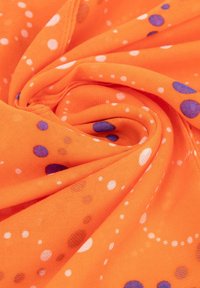 Oranje stof met een gladde textuur, voorzien van een patroon van grote paarse en witte stippen, die in een verspreid patroon zijn gerangschikt.