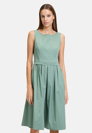 Ein ärmelloses, knielanges Kleid aus weichem, hellgrünem Stoff, mit einem taillierten Oberteil und einem gerafften Rock mit glatter Textur.