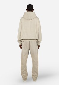 Μπεζ φούτερ με κουκούλα και αντίστοιχες παντελόνες από μαλακό ύφασμα, με άνετη εφαρμογή, ριμπ μανίκια και μέση.