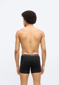 Μαύρο ανδρικό μπόξερ με ελαστική ζώνη μέσης με το λογότυπο "TOMMY HILFIGER" σε λευκό χρώμα. Τα μπόξερ είναι εφαρμοστά και με λεία υφή.