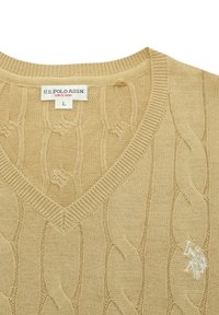 Pulover bej tricotat, cu decolteu în V, model cu torsade și logo brodat pe partea stângă a pieptului. Eticheta indică U.S. Polo Assn. și mărimea L.