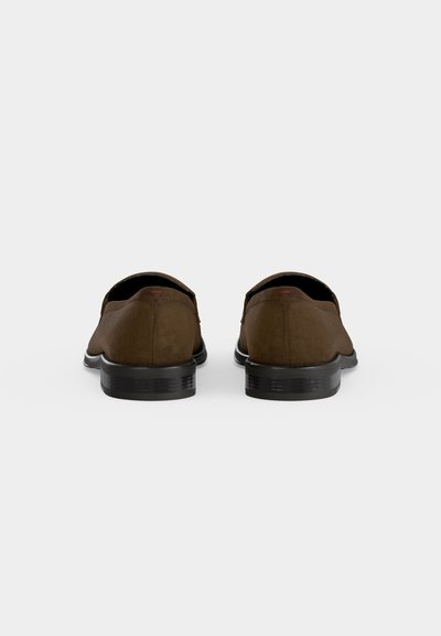 Paire de chaussures en daim marron à enfiler, vues de dos avec des talons bas noirs sur fond blanc.