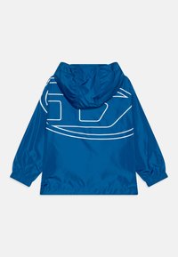 Blå lett jakke med hette, med et hvitt grafisk design på ryggen. Elastiske mansjetter og hem, jevn tekstur, vannavstøtende materiale.