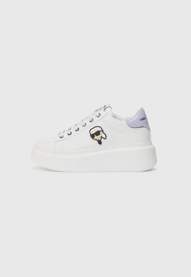 White platform sneakers with a leather upper, featuring a black and white logo patch, silver eyelets, and a lavender heel accent.