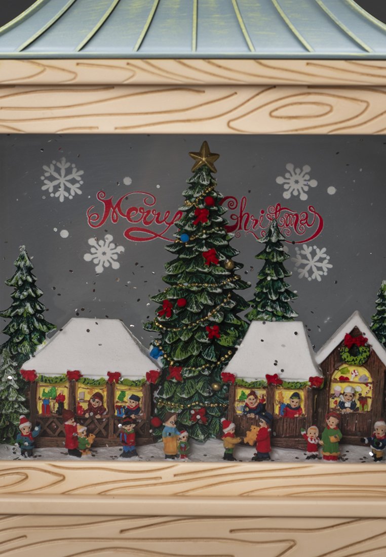 Escena navideña con casas cubiertas de nieve, árbol decorado, niños jugando y el texto "Feliz Navidad" con copos de nieve.