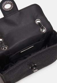 Borsa nera con esterno texture, hardware argentato, dettaglio a catena e interno dotato di tasca e placca con logo.