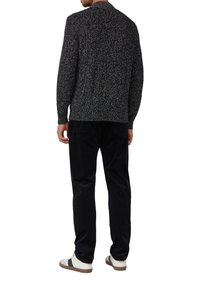 Maglione grigio-nero lavorato a maglia con un motivo testurizzato, abbinato a pantaloni in velluto a coste scuri e sneakers bianche con dettagli marroni.