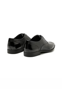 Scarpe eleganti nere con tomaia in mesh testurizzato e dettagli lucidi in vernice; punta arrotondata, profilo basso e chiusura con lacci. Suola in gomma durevole.