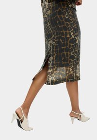 Gonna di seta con stampa leopardo e spacco laterale, caratterizzata da una texture liscia. Abbinata a tacchi di colore crema con un design di tacco geometrico unico.