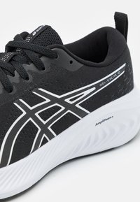 Black running shoe with a mesh upper, white accents, and a rubber sole. Features minimalistic design elements and textured patterns on the surface.