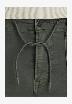Pantalons vert olive avec cordon de serrage et fermeture à bouton, dotés d'une texture lisse et de subtiles coutures sur le tissu.