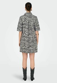 Robe à manches courtes avec un motif zèbre noir et gris, réalisée en tissu léger, avec un col à revers et une coupe droite.