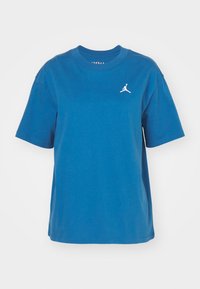 Modrá bavlněná trička s kulatým výstřihem, krátkými rukávy a bílým vyšitým logem Jumpman na levém prsu. Hladká textura, volný střih.