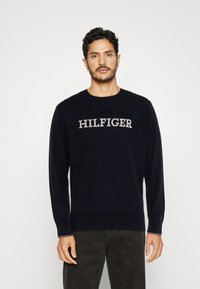 Maglione a maniche lunghe blu navy con la scritta grigia "HILFIGER" sul petto. Collo e polsini a coste, tessuto morbido con una superficie liscia.