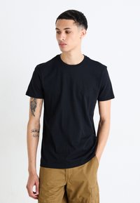 Tricou din bumbac negru cu guler rotund și mâneci scurte, având o textură netedă și un design ajustat. Fără modele sau logo-uri vizibile.