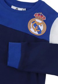 Blauw en marineblauw shirt met lange mouwen met een wit mouwgedeelte, met het logo van voetbalclub Real Madrid op de borst bij de kraag.