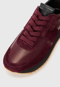 Botte de sport bordeaux en mélange de daim et de cuir, avec des lacets ronds et une semelle en caoutchouc texturée dotée d'une semelle extérieure en gomme contrastante.