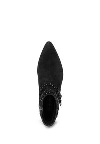 Zwarte suède enkellaars met puntige neus, zilveren studs en twee zijgespen, van bovenaf gezien op een witte achtergrond.