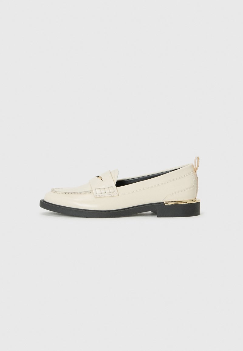 Cream leather loafer with a decorative strap, stitched details, and a low black platform sole accented with a gold heel.