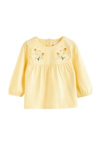 Gelbes Langarmoberteil mit elastischen Bündchen, das mit floralen Stickereien in Orange und Grün verziert ist, sowie einem Rundhalsausschnitt mit einer Knopfverschluss auf der Rückseite.