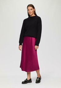 Schwarzer gestrickter Pullover, magentafarbener Satin-Midi-Rock und schwarze lackierte Lederloafer. Glatte Texturen und kontrastierende Farben.