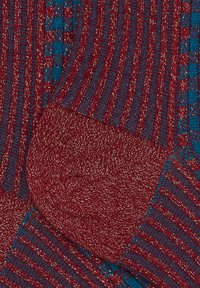 Calzini a righe rosse e blu con filo metallico. Tessuto a coste, sezioni del tallone e delle punte a contrasto. Materiale in maglia morbido in tutto il calzino.