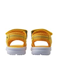 Gule sandaler med polstret anklestropp og reflekterende striper. Hvit gummiyttersåle med teksturert gripeprofil. Åpen bakdesign.