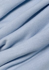 Helles blaues Strickgewebe mit weicher Textur, das dezente Rippen und eine glatte Oberfläche aufweist, drapiert und geschichtet.