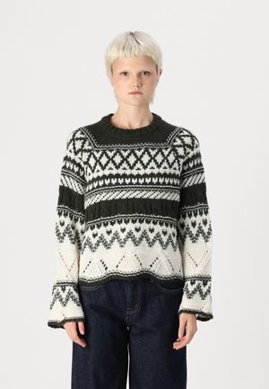 Pull en tricot avec un motif géométrique vert et blanc, col rond et manches larges, fabriqué en fil texturé.