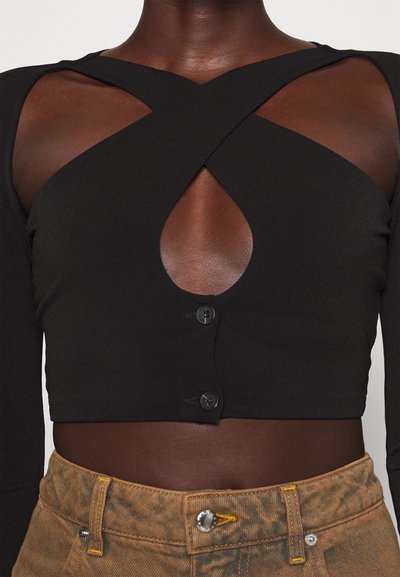 Top corto negro con mangas largas, que presenta un diseño con corte y cierre de botones. Fabricado en tela suave, con una forma ajustada.